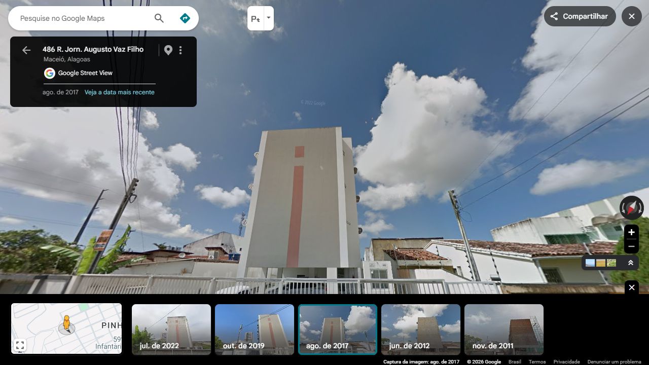 O topo e as sacadas do edifício branco e coral